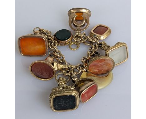 A 9ct gold curb-link fob bracelet, each link stamped, to include a gold mounted tooth, a gem-set watch winder and nine Georgi