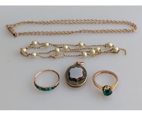 A turquoise ring on a rose gold setting, an emerald ring in a yellow gold claw setting, a fob medal and two neck chains, one 