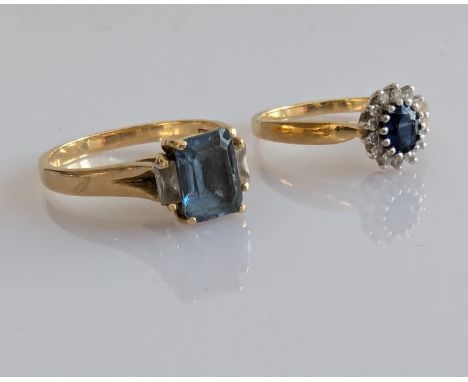 A baguette-cut blue topaz ring in a yellow gold claw setting, stone 8 x 6mm and an oval sapphire cluster ring with diamond de