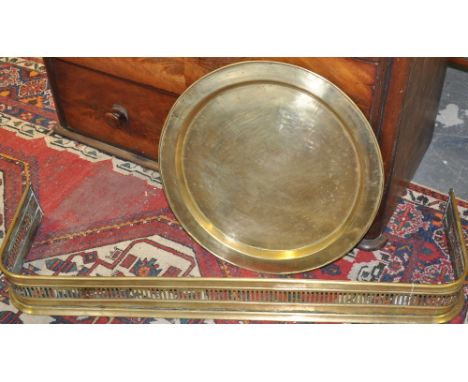 A Victorian brass fender together with a large circular brass tray