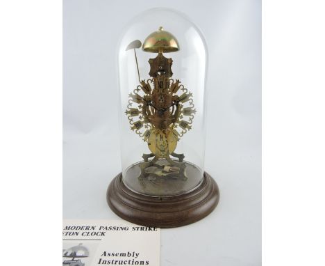 A 20th century skeleton brass clock with a pierced dial set out in Roman numerals, on a circular turned base and under a glas
