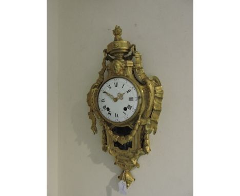 A Louis XV design ormolu cartel clock, the ribbon fold floral swag cast case with female mask beneath a torch trophy, the bra