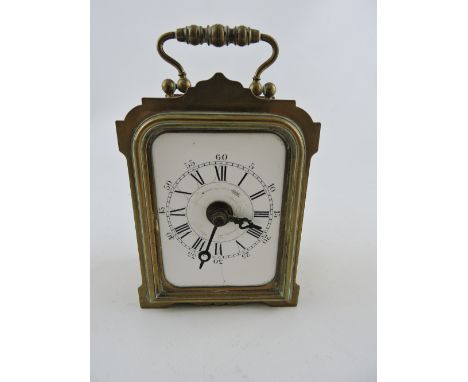 An early 20th century French alarm clock, with a shaped brass case and a white ceramic dial, H. 11cm.