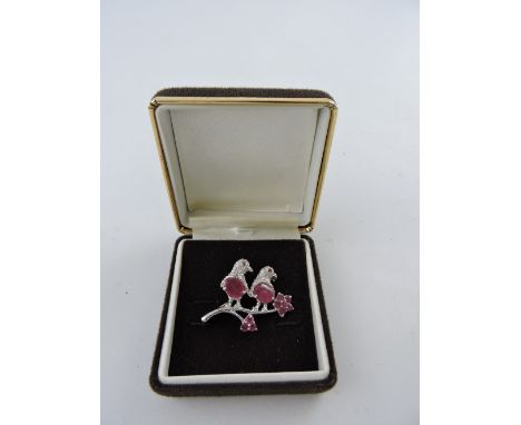 A white metal and ruby set brooch, modelled as two birds on a flowering branch, 7.5g.