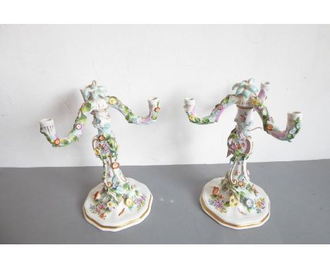 A pair of late 19th century German porcelain three-light candelabra (some damage); the removeable arms encrusted with various