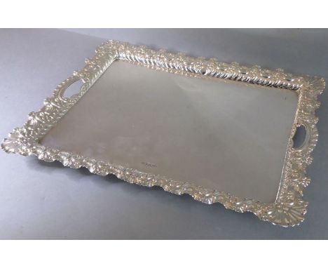 A fine hallmarked silver two-handled serving tray; the raised border decorated in relief with C scrolls and foliate-style orn