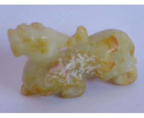 A Chinese celadon jade carving of a mythical beast; the celadon and russet coloured jade showing signs of calcification, the 
