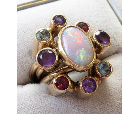 An unusual 9-carat yellow gold triple band ring; the central band with an oval opal flanked by two amethysts, the other bands