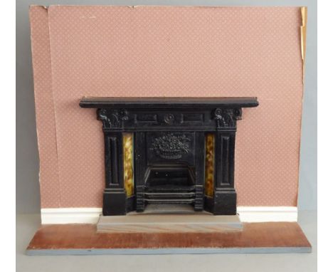 A miniature black-painted cast-iron fireplace; in 19th century style, of ornate design and with three horizontal bars flanked