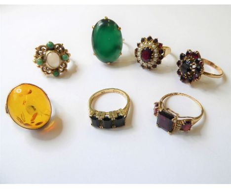 Seven assorted gem-set rings: three garnet set and yellow gold rings, a 9-carat yellow gold scrolling ring collet-set with an