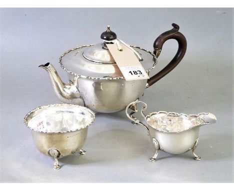 An early 20th century three-piece hallmarked silver tea service: teapot, circular sugar and creamer. Each with raised serrate