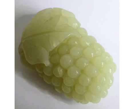 A Chinese pale celadon jade carving of grapes and vine leaves, together with a similar sized carved jade netsuke of a monkey-