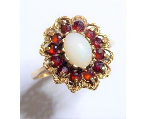 A 9-carat yellow-gold dress ring centrally set with a cabochon opal surrounded by twelve garnets, ring size P, boxed (3.2g)