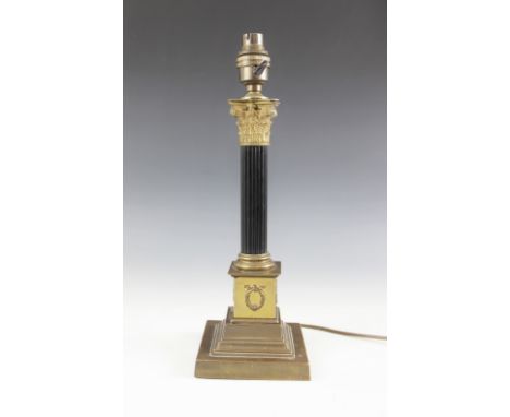 A brass mounted column table lamp, early 20th century, the brass Corinthian capital set to a reeded ebonised column on steppe