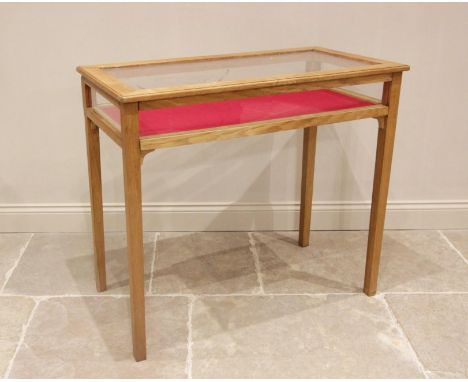 A contemporary light oak bijouterie cabinet, late 20th century, the hinged and glazed top raised upon legs of tapering square