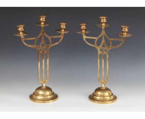 A pair of early 20th century brass Art Nouveau candelabra in the Mackintosh style, each with three branches upon an openwork 