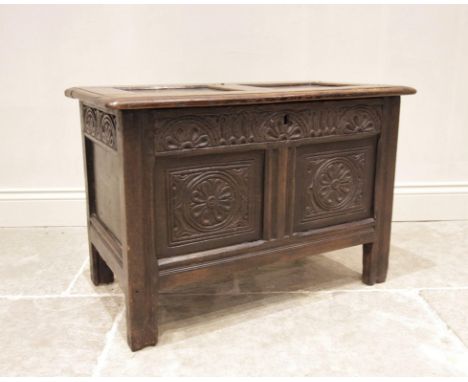 An early 18th century oak coffer bach, the twin panelled top above a nulled and lunette carved frieze, and two panels each ce