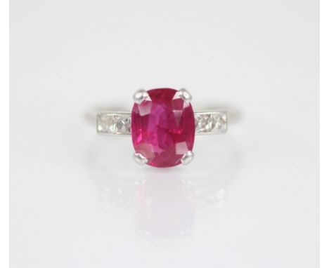 An Art Deco ruby and diamond ring, the central (untested) rectangular cushion cut ruby measuring 8.95mm x 7.14mm x 4.41mm, wi