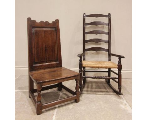An 18th century oak low seat chair, the panelled back above a board seat, raised upon front baluster turned legs and plain re