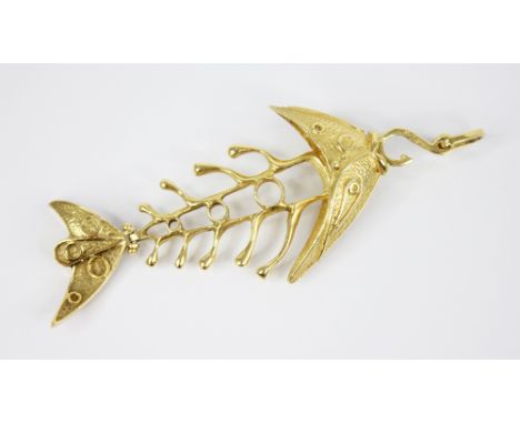 A gold coloured abstract fish pendant, with plain polished pierced skeletal body, the articulated head and tail with textured