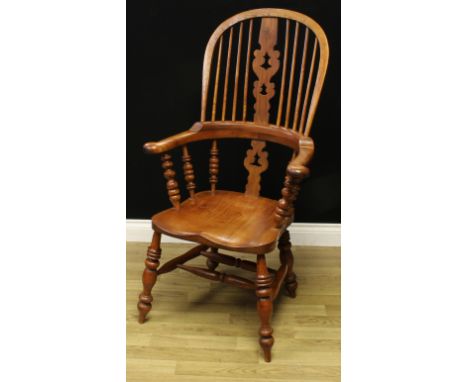 An ash and elm Windsor elbow chair, hoop back, shaped Christmas tree splat, bowed mid rail terminating in outswept hand rests