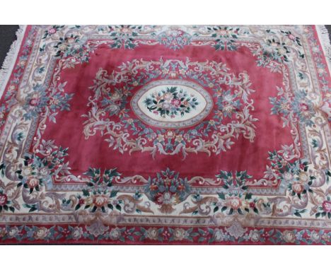 A Chinese woollen carpet, with central floral cartouche, the ground with scrolls on a pink ground, approx 9ft x 12ft 