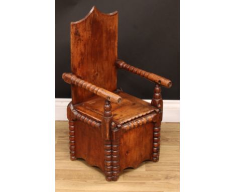 A 19th century pine child's box chair, rectangular shield shaped back, bobbin-turned arms, hinged seat enclosing a commode ap