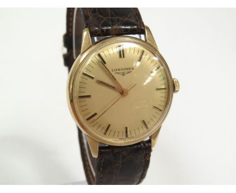 LONGINES: A 9ct gold cased Longines wristwatch on leather strap, champagne dial with gilt and black line markers, with centre