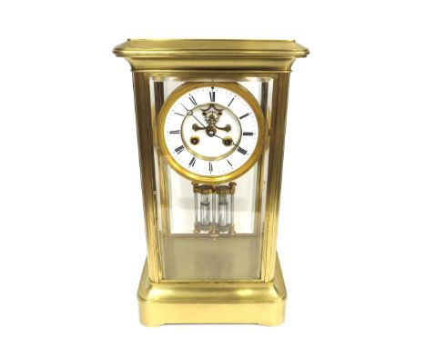 A 20th Century brass mantel clock with bevel edge glass panels to each side, suspended circular dial with Roman chapter ring 