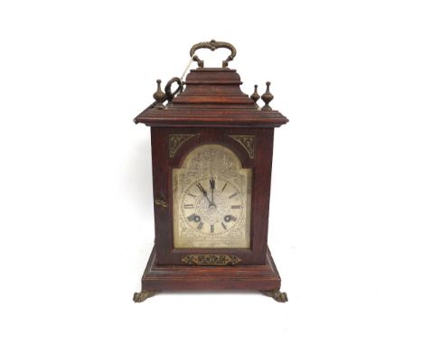 An early 20th Century oak cased bracket clock, ornate silvered Roman dial, case on brass paw feet, with pierced brass lattice