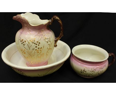 An early 20th century oil lamp with smokey glass shade and resevoir, together with a matching pottery jug, basin and chamber 