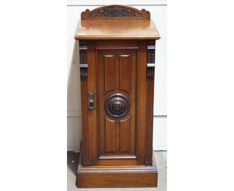 A Victorian walnut square bedside cupboard, with single door with column sides and carved roundel, opening to reveal a shelf,