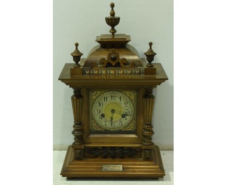 A Victorian walnut mantel clock, with carved finials, silvered and gilded dial and supported on a stepped base with column si