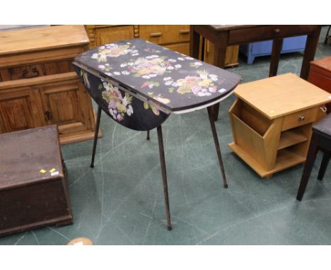 A vintage drop leaf table, the top printed with flowers and fruits, and raised on metal legs