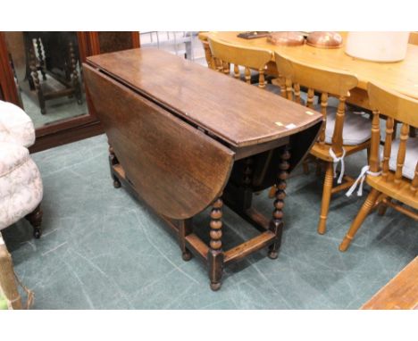 An oak drop leaf and gate leg table raised on turned supports