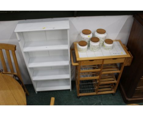 A pine tile topped kitchen trolley on wheels and a free standing white bookcase
