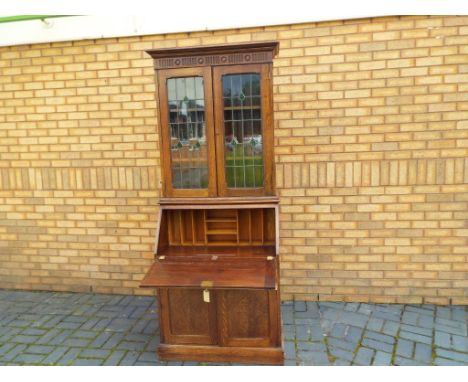 An oak bureau bookcase, the slope front opening to reveal a pigeon-hole fitted interior above single drawer and cupboard, man