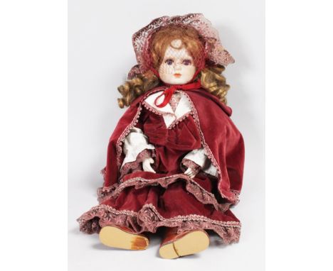 A GOOD GERMAN BISQUE HEADED DOLL wearing a velvet cloak.