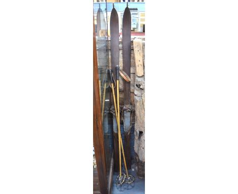 A pair of vintage wooden skis with leather strap bindings, to/w a pair of bamboo ski-poles with stitched leather grips