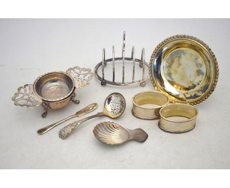 Various table silver including a toast-rack, tea strainer and associated stand, caddy spoon with shell bowl (1973), two napki