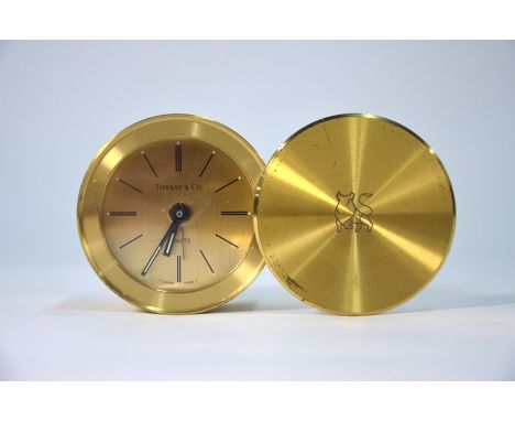 A Tiffany &amp; Co lacquered brass travel alarm clock with quartz movement, in drum case with revolving cover, 6 cm diam