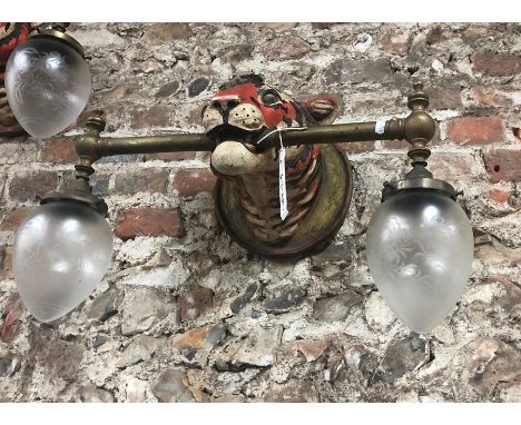 An unusual pair of 'Tiger' mask wall lights, the polychromed composite heads mounted with brass twin light bars, 25 cm dia. x