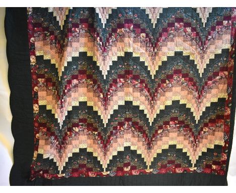 A vintage American Amish hand-sewn patchwork quilt in hues of burgundy and dark green with green floral printed backing and s