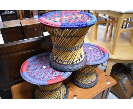 A set of three ethnic art style stools or occasional tables having woolwork tops with woven frames and recycled tyre bases, e