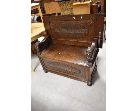 An early 20th Century oak monks bench having figural carved arms and vine applique decoraion, width approx. 99cm