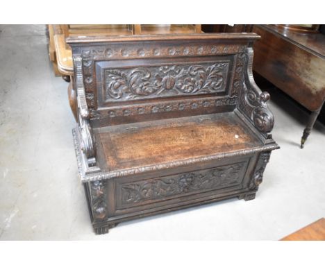 A 19th Century oak monks bench having heavily carved decoration, width approx. 108cm