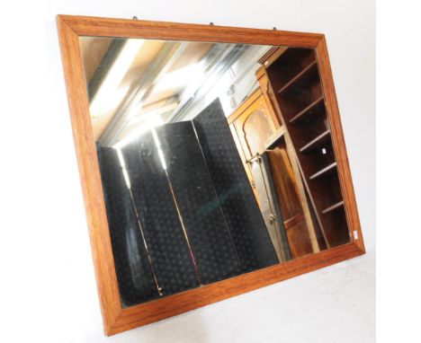 A large early 20th century oak overmantel shop mirror. The large mirror having central plate mirror glass within a golden oak