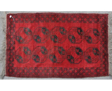 A vintage mid 20th century Afghan Esari Persian Islamic carpet floor rug. Having repeating central medallions in red ground i