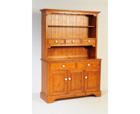 A vintage 20th century country pine kitchen dresser. Rectangular form with pediment top, shelving / plate rack above three sm