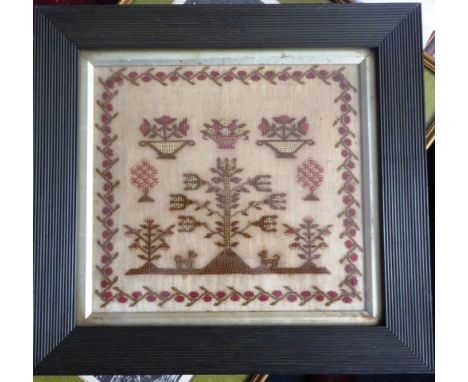 A framed and glazed 19th century needlework sampler depicting bowls of flowers in a central tree with two dogs flanking, all 